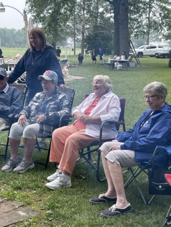 a group of people gathered outside in lawn chairs
